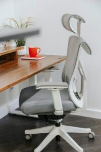 Ergonomic mesh office chair with headrest next to a wooden desk