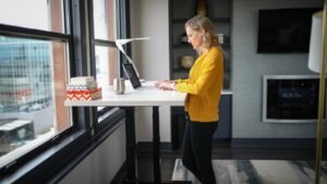Woman standing at an adjustable-height desk working on a laptop